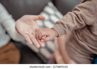 Hands Holding Of Mother Parent Soft Touch Newborn Baby Fingers Love Family Concept. Infant Child Portrait Happy Healthy.