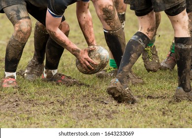 Hands Holding A Muddy Rugby Ball, Close Up Image