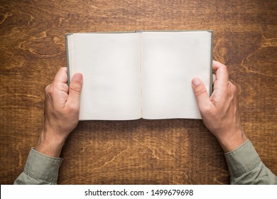 Hands Holding Open Book On The Table