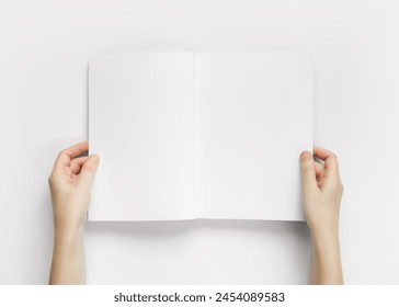 Hands holding an open magazine with empty white pages top view