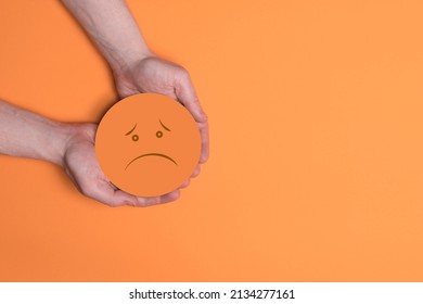 Hands holding orange sad smile, bad feedback rating, negative customer review, bad experience, unsatisfied survey, mental health assessment, child wellness concept, 