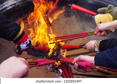 Hands holding out and lightening incense over an open fire at the Tibetan Buddhist Monastery at the to of Emei Mountain/Emei Shan in Sichuan Province, China.