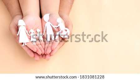 hands holding paper Cutout of different family members being together.