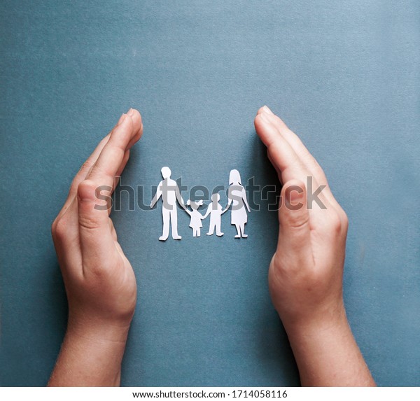 hands\
holding paper family cutout, social distancing concept, covid19  on\
the blue color background, family\
protection