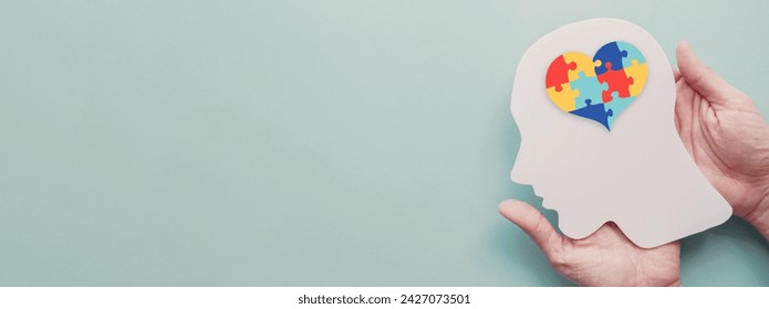 Hands holding  paper head with jigsaw puzzle heart shape, Autism awareness,Autism spectrum disorder family support concept, World Autism Awareness Day - Powered by Shutterstock