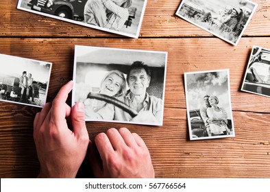Hands holding pictures of senior couple. Studio shot, wooden bac - Shutterstock ID 567766564