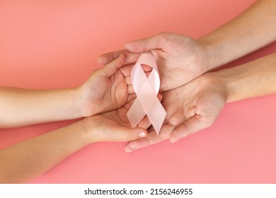 Hands holding pink ribbon on pink background, Breast cancer awareness and October Pink day, world cancer day, national cancer survivor day. - Shutterstock ID 2156246955