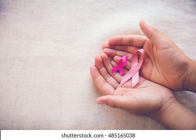 Hands holding Pink Ribbons on toning background, Breast cancer day awareness, October Pink and Abdominal cancer awareness, world cancer day