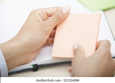 Hands holding pink sticky note with empty space