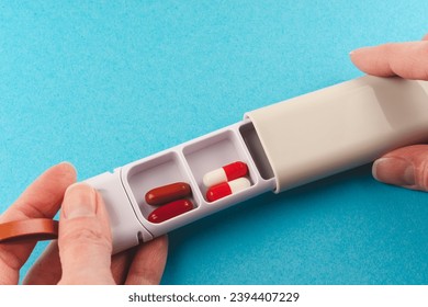 hands holding a plastic white organizer tablet box on a blue background. - Powered by Shutterstock