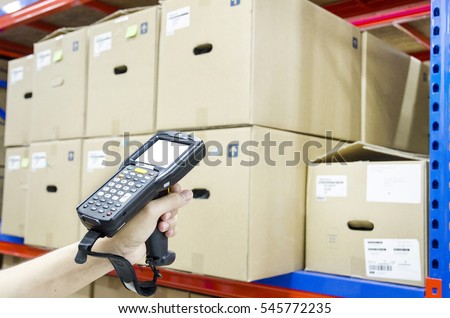 Hands holding portable barcode scanner in warehouse 
