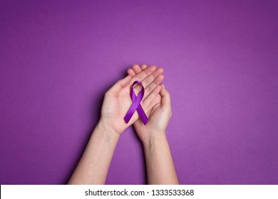 Hands holding Purple ribbons on a purple background. World epilepsy day. Alzheimer's disease, Pancreatic cancer, Epilepsy awareness, fibromyalgia awareness.