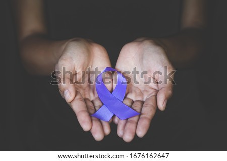 Hands holding Purple ribbons,  Pancreatic cancer, Epilepsy awareness, domestic violence awareness, Alzheimer disease, fibromyalgia awareness, world cancer day.
