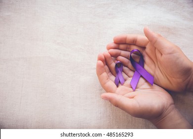 Hands holding Purple ribbons, toning copy space background, Alzheimer's disease, Pancreatic cancer, Epilepsy awareness, fibromyalgia awareness,world cancer day