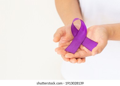 Hands holding purple or violet ribbon on white fabric with copy space. Pancreatic Cancer ,Testicular Cancer Awareness, Cancer Survivor, Leiomyosarcoma, World Cancer Day. Healthcare, insurance concept. - Shutterstock ID 1913028139