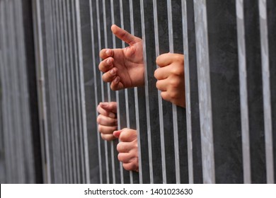 Hands holding and reaching out of strong iron bars. Prison or immigrant and refugee crisis in Europe, USA and Mexico. Dramatic border fence or concept 