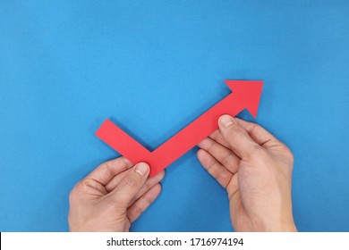 Hands Holding A Red Arrow Going Up. Economy And Stock Market Bounce Back And Recovery Concept. 