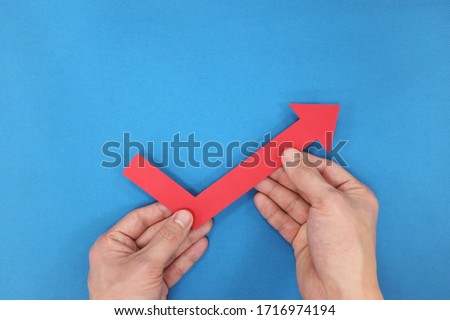 Hands holding a red arrow going up. Economy and stock market bounce back and recovery concept. 