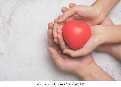 Hands holding a red heart on cement background, CSR or Corporate Social Responsibility, health care, family insurance, heart donate concept, world health day.