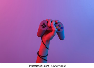 Hands holding retro joystick in blue-red neon gradient light. Old gaming. 80s retro wave. Minimalism - Powered by Shutterstock