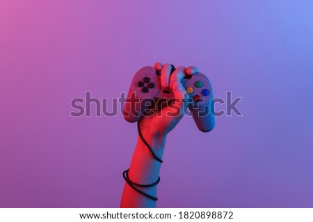 Hands holding retro joystick in blue-red neon gradient light. Old gaming. 80s retro wave. Minimalism