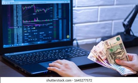 Hands holding Russian rubles in front of a computer monitor with the currency market and Forex trading chart. Trading stocks, bonds, and securities on the stock exchange. Trader in Russia with ruble. - Powered by Shutterstock - Get 15% off with code: PIKWIZARD15