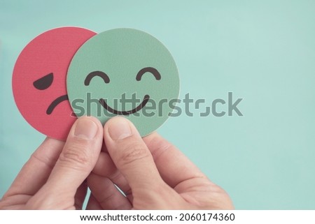 Hands holding sad face hiding behind happy face, bipolar and depression, mental health, split personality,  mood change, 