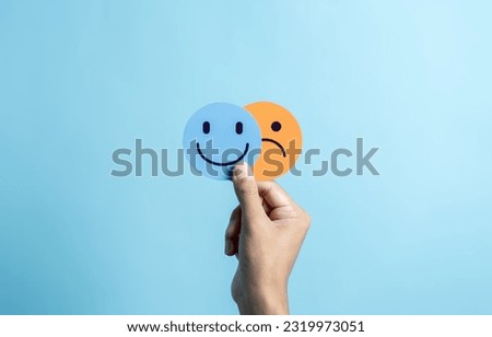 Hands holding sad face hiding or behind happy smiley face, bipolar and depression, mental health concept, personality, mood change, therapy healing split concept.