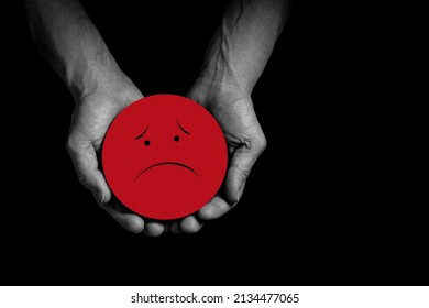 Hands holding sad smile, bad feedback rating, negative customer review, bad experience, unsatisfied survey, mental health assessment, child wellness concept, Red face on black background copy space.