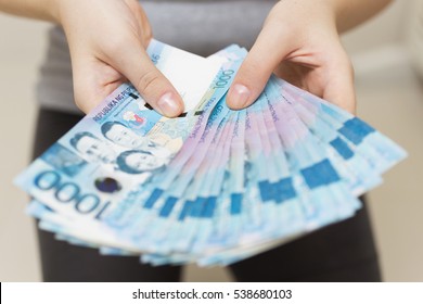 Hands holding salary or payment bundle of cash of one thousand philippines peso as if being rich. Show off, pay bills or give bribe.