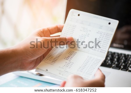 hands holding saving account passbook, book bank  laptop background