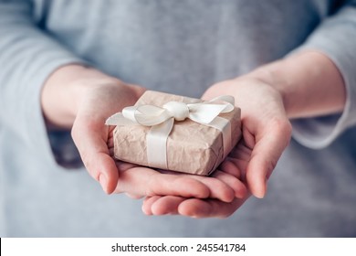 Hands Holding Small Paper Gift Box. Toned Picture