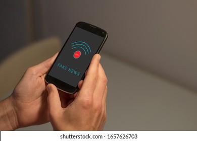 Hands holding smartphone with fake news and send button on the screen. - Shutterstock ID 1657626703