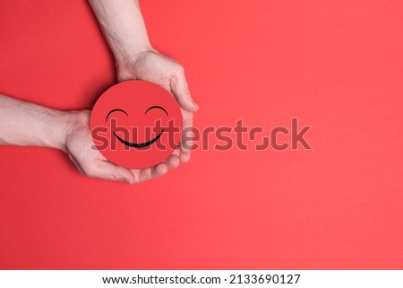 Hands holding smile, great feedback rating, positive customer review, good experience, satisfied survey, mental health assessment, child wellness concept, Red face on red background copy space.