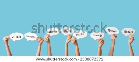 Hands holding speech bubbles with text THANK YOU in different languages on blue background