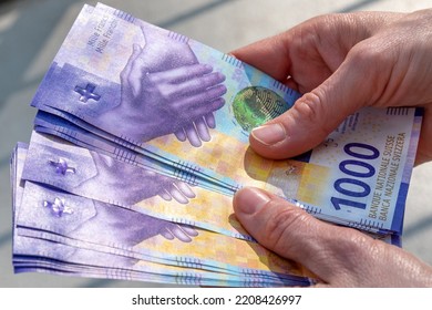 hands holding a stack of swiss francs money - Shutterstock ID 2208426997