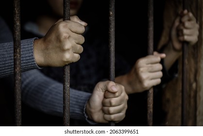 Hands holding a steel cage in old iron bar. Restriction of the rights of human.