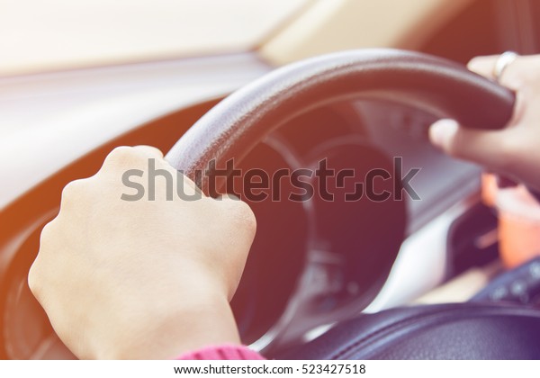 Hands holding steering wheel in car with vintage\
tone filter