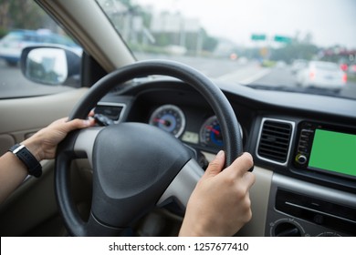 Hands holding steering wheel while driving car on city road