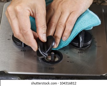 Hands Holding Stove Knob Dial With Rag Underneath