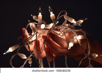 the hands holding string lights