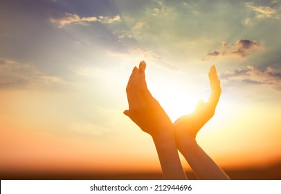 hands holding the sun at dawn
