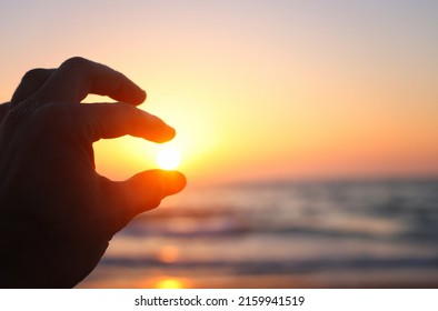 Hands Holding The Sun At Evening. Sea Background. Summertime And Vacation Concept