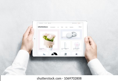 Hands holding tablet with gifts webstore mock up on screen, isolated. Clothing web page interface mockup. Internet website online template on the device display.