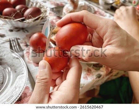 Hands holding and tapping red Easter eggs over a festive table during a traditional holiday breakfast celebration