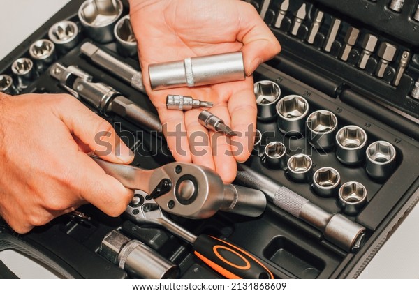 Hands holding tools wrench and nuts on the\
background of a box for a\
motorist.