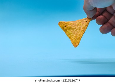 hands holding triangle doritos or nachos, on blue background, ideal copy space