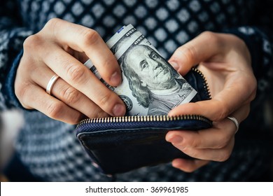 Hands holding us dollar bills and small money pouch - Powered by Shutterstock