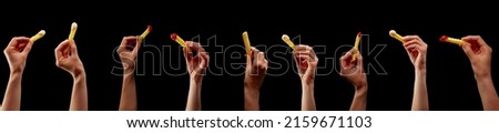 Hands holding various chips, pommes, or french fries on isolated black background as construction material for bbq or fast food advertisement