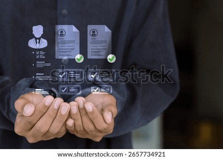 Hands holding virtual HR interface with employee resumes, profile checks, and data management system.